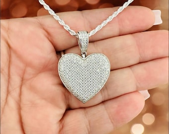May include: A silver heart-shaped pendant necklace with a rope chain. The pendant is covered in small, clear stones.
