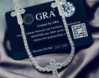 May include: A silver chain necklace with a large, diamond-encrusted cross pendant. The chain is made of small, round diamonds. The necklace is displayed on a black card with the text "GRA" and "Warranty ID:GRA 322 382".