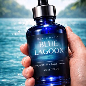 K&ouml;nnte beinhalten: Eine dunkelblaue Glasflasche mit schwarzer Pipette und silbernem Kragen wird vor einem blauen Wasserhintergrund gehalten. Auf dem Etikett steht "ISLAND MAGIC BLUE LAGOON" mit den unten aufgef&uuml;hrten Inhaltsstoffen. Die Flasche enth&auml;lt 118 ml.