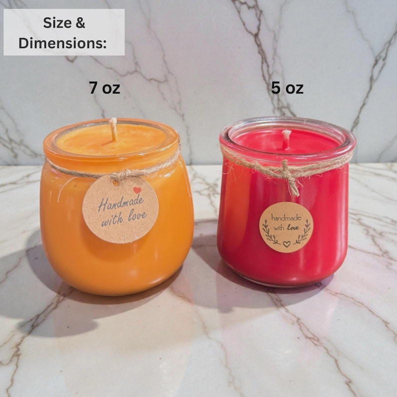 Puede incluir: Dos velas en tarro de cristal, una naranja y otra roja, con hilo y etiquetas que dicen "hecho a mano con amor". La vela naranja es de 198g, y la vela roja es de 142g. Ambas velas tienen un tarro de cristal transparente.