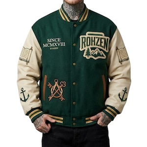 Può includere: Una giacca varsity verde scuro con maniche color crema, dotata di chiusura con bottoni a pressione, colletto e polsini a coste a righe e toppe ricamate tra cui il testo "SINCE MCMXVIII ROHZEN", un paesaggio montano, chiavi, libri e ancore.