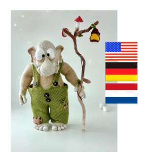 Peut inclure: Poupée troll au crochet faite à la main, avec un visage beige, de grands yeux blancs et un long nez. Le troll porte une salopette vert olive et tient un bâton marron avec un champignon et une lanterne. La poupée mesure environ 25 cm de haut.