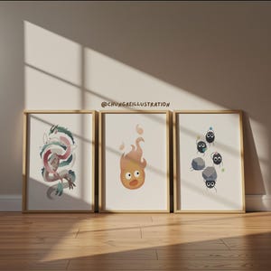 May include: Three framed art prints featuring illustrations of a dragon, a fire spirit, and soot sprites. The dragon is in shades of pink, green, and white. The fire spirit is orange. The soot sprites are black with blue accents.