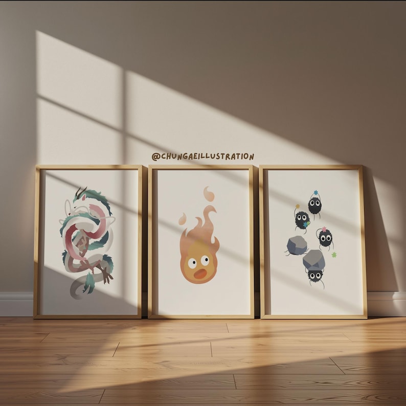 May include: Three framed art prints featuring illustrations of a dragon, a fire spirit, and soot sprites. The dragon is in shades of pink, green, and white. The fire spirit is orange. The soot sprites are black with blue accents.