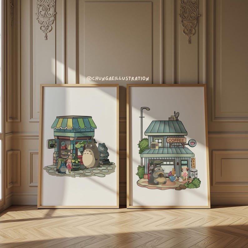 May include: Two framed art prints featuring illustrations of Studio Ghibli characters. One print depicts a shop with a green and blue awning, and the other shows a coffee shop. The prints are in wooden frames and are displayed on a light-colored wall.