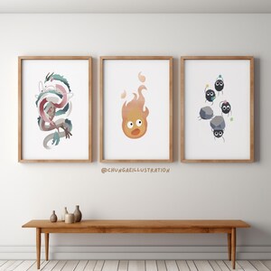 May include: Three framed art prints featuring watercolor illustrations. One depicts a dragon in shades of blue, pink, and white. Another shows a flame with a face, and the third displays soot sprites with rocks. The prints are in wooden frames.
