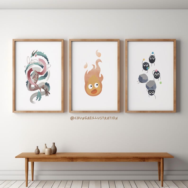 May include: Three framed art prints featuring watercolor illustrations. One depicts a dragon in shades of blue, pink, and white. Another shows a flame with a face, and the third displays soot sprites with rocks. The prints are in wooden frames.