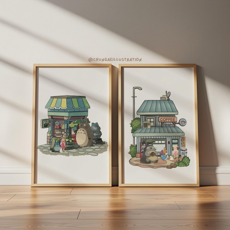 May include: Two framed art prints featuring illustrations of buildings with cartoon characters. One print shows a building with a green and blue striped awning, and the other shows a coffee shop. The prints are in wooden frames.