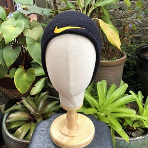 Peut inclure: Bonnet noir en tricot avec un logo Nike jaune en forme de virgule.