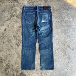 Op de afbeelding: Blauwe denim jeans met een vervaagde wassing en distressed details. De jeans hebben een klassiek vijf-zakken ontwerp, een knoop- en ritssluiting en een leren patch met de merknaam. De achterzakken hebben een kenmerkende gebogen stiksel.