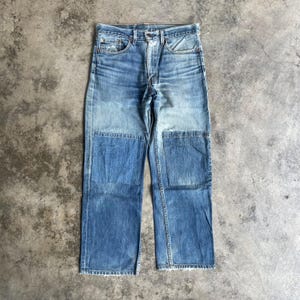 Op de afbeelding: Lichtblauwe spijkerbroek met patchworkdetails aan de voorkant. De jeans heeft een knoop- en ritssluiting, met een klassieke vijf-zakken-stijl. De denim heeft een verweerde, versleten uitstraling.