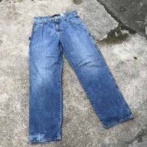May include: A pair of blue denim carpenter jeans with a faded look. The jeans have a straight leg and multiple pockets.