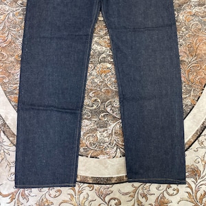May include: Dark blue denim jeans. The jeans have a classic five-pocket design with a straight leg cut. The fabric appears to be a medium-weight denim, and the jeans are unwashed. The image shows the jeans from the waist down.