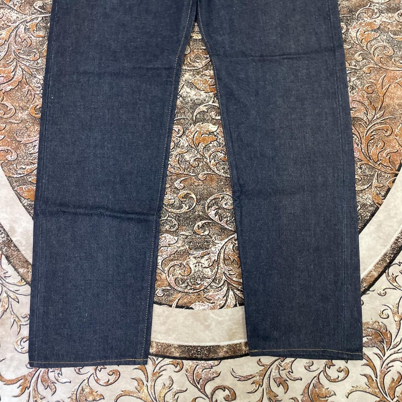 May include: Dark blue denim jeans. The jeans have a classic five-pocket design with a straight leg cut. The fabric appears to be a medium-weight denim, and the jeans are unwashed. The image shows the jeans from the waist down.