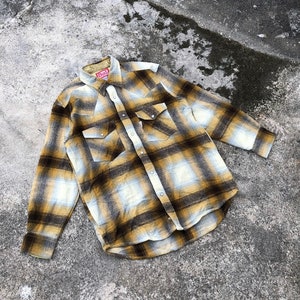 May include: A yellow and brown plaid flannel shirt with a red "Bud" label on the left side of the collar.
