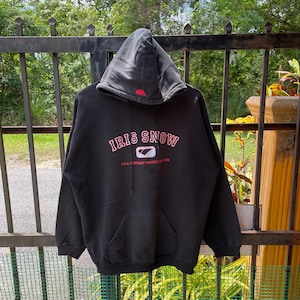 Puede incluir: Sudadera con capucha negra con el texto "IRIS SNOW" en letras rosa y rojas. El texto "FULL CONTACT WINTER SPORTS" está impreso en blanco debajo del logotipo.