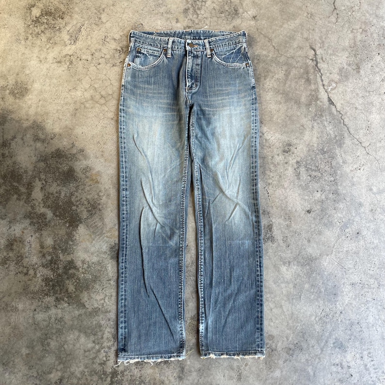 May include: Faded blue denim jeans with a classic five-pocket design. The jeans have a button fly and a straight leg cut. The denim shows signs of wear and fading, giving them a vintage look.