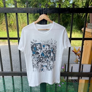 May include: White t-shirt with a black and white graphic print of a collage of faces and text. The text includes "BURN", "MINIMALIST", and "THE KIDS ARE ALRIGHT".