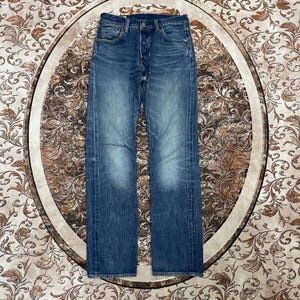 May include: A pair of blue denim jeans featuring a classic five-pocket design, a button fly closure, and a faded wash finish. The jeans have a straight-leg cut with visible stitching along the seams and a standard waistband with belt loops.