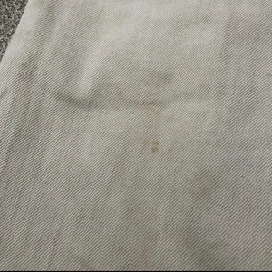 May include: A close-up of a light beige fabric with a subtle woven texture. The fabric has a slight discoloration in the center.