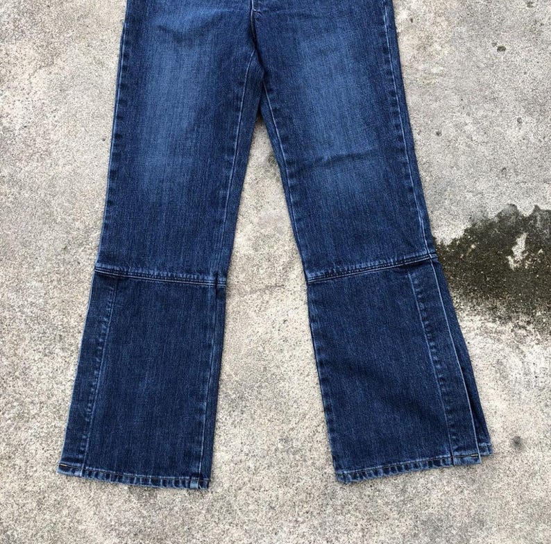 Op de afbeelding: Een paar donkerblauwe spijkerbroeken met een wijde pijp en een uitlopende zoom. De broek heeft een naad aan de voorkant van elk been en een naad aan de achterkant van elk been.