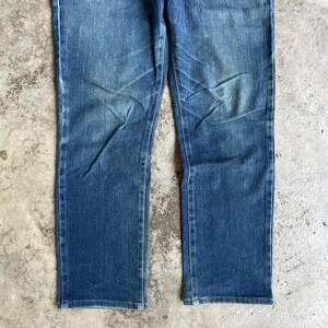 Op de afbeelding: Blauwe denim jeans met een rechte pijp. De jeans hebben een vervaagde wassing en subtiele slijtplekken, waardoor ze een vintage look hebben. De stof lijkt een mediumgewicht denim te zijn.