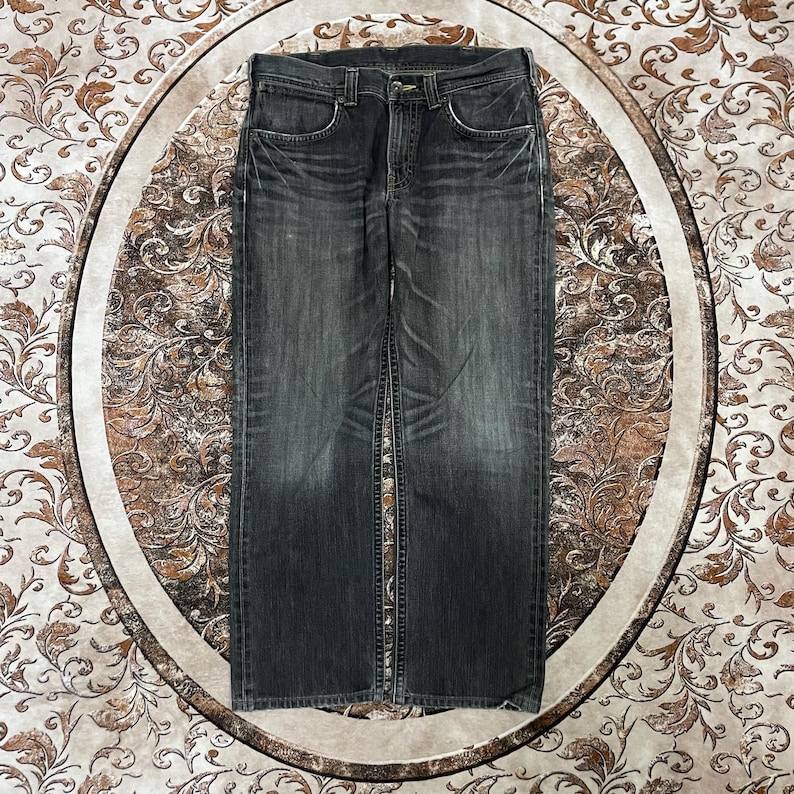 May include: Dark gray denim jeans with a classic five-pocket design. The jeans have a faded appearance and a straight leg cut. The image shows the jeans laid flat, showcasing the front and back details, including the button and zipper closure.