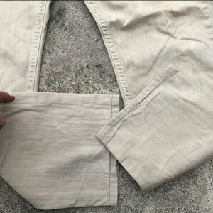 May include: A pair of light beige denim pants with a straight leg and a slightly faded appearance.