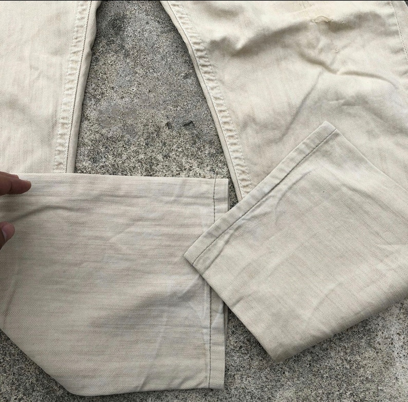 May include: A pair of light beige denim pants with a straight leg and a slightly faded appearance.
