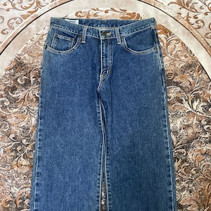 Puede incluir: Vaqueros de mezclilla azul con un dise&ntilde;o cl&aacute;sico de cinco bolsillos. Los vaqueros tienen un corte de pierna recta y un cierre de bot&oacute;n y cremallera. La mezclilla tiene un lavado medio con decoloraci&oacute;n sutil y marcas de desgaste.