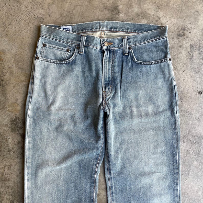 May include: Light blue denim jeans with a classic five-pocket design. The jeans have a faded wash and a straight leg cut. The front features a button closure and a zipper fly. The jeans are made of a durable denim material.