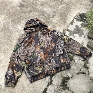 May include: Camouflage hooded jacket with a zipper closure and a large pocket on the front. The jacket is made of a soft, durable fabric and features a woodland camo pattern.
