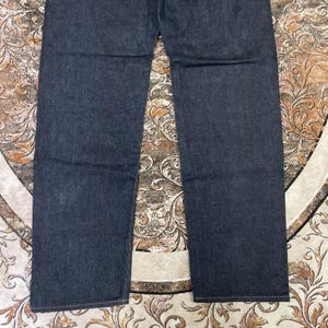 May include: Dark blue denim jeans. The jeans have a classic five-pocket design and a straight leg cut. The fabric appears to be a medium weight denim.
