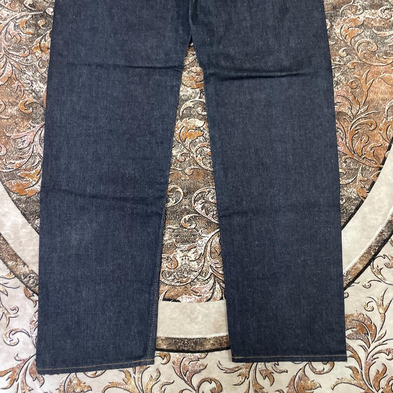 May include: Dark blue denim jeans. The jeans have a classic five-pocket design and a straight leg cut. The fabric appears to be a medium weight denim.
