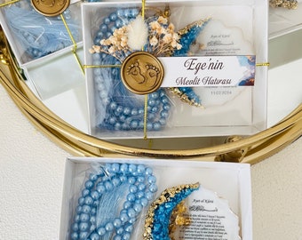 May include: A set of three blue and gold baby boy's mevlüt hatırası favors. Each favor includes a blue prayer bead necklace, a gold and blue crescent moon charm, and a white card with the text "Ege'nin Mevlit Hatırası 11.02.2024".