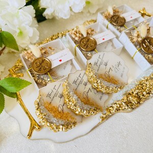 May include: A set of four white and gold resin coasters with a thank you message and the date 2023.11.18. The coasters are displayed on a white tray with a gold branch.