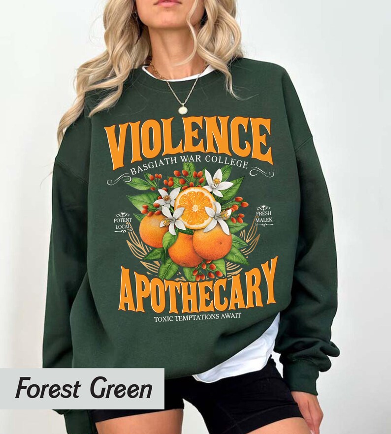 Puede incluir: Sudadera verde bosque con la palabra "VIOLENCE" en naranja, encima de "BASGIATH WAR COLLEGE". Debajo, "APOTHECARY" est&aacute; impreso en naranja, con una ilustraci&oacute;n de naranjas, flores y hojas. El texto "TOXIC TEMPTATIONS AWAIT" est&aacute; debajo.