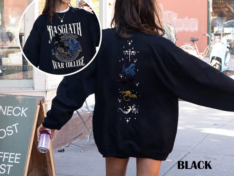 Puede incluir: Sudadera negra con el texto "Basgiath War College" y un dise&ntilde;o de drag&oacute;n en la parte delantera. La parte trasera presenta un dise&ntilde;o vertical de dragones y estrellas. La palabra "BLACK" est&aacute; impresa en la parte inferior derecha.