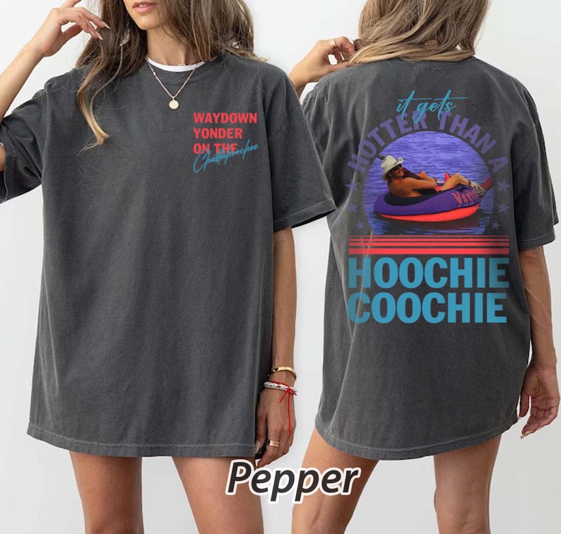 May include: Dark grey t-shirt with the text "WAYDOWN YONDER ON THE Christopher" on the front. The back of the shirt features a graphic of a person in a tube with the text "it gets HOTTER THAN A HOOCHIE COOCHIE".