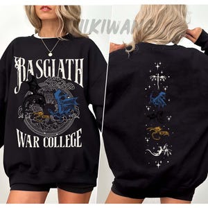 Puede incluir: Sudadera negra con ribete blanco, con el texto "BASGIATH WAR COLLEGE" y un gr&aacute;fico circular de dragones. La parte trasera muestra una l&iacute;nea vertical de ilustraciones de dragones.