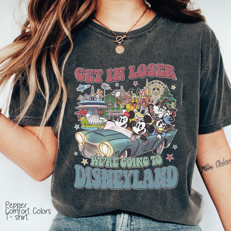 Puede incluir: Camiseta gris oscuro con un gr&aacute;fico de Mickey Mouse y sus amigos en un coche antiguo, con el texto "GET IN LOSER WE'RE GOING TO DISNEYLAND". La camiseta es una camiseta Pepper Comfort Colors.