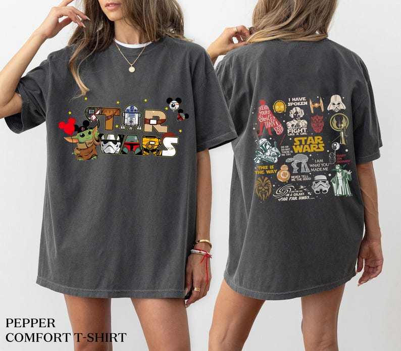 May include: Dark grey Star Wars graphic t-shirt. The front features the words "STAR WARS" with cartoon characters. The back of the shirt has various Star Wars character illustrations and text. The shirt is a comfort t-shirt.