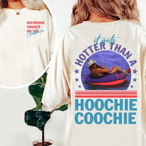 May include: Cream-colored t-shirt with the text "Waydown Yonder on the Chattahoochee" on the front. The back of the shirt features a graphic of a person in a tube on the water with the text "It gets hotter than a Hoochie Coochie".