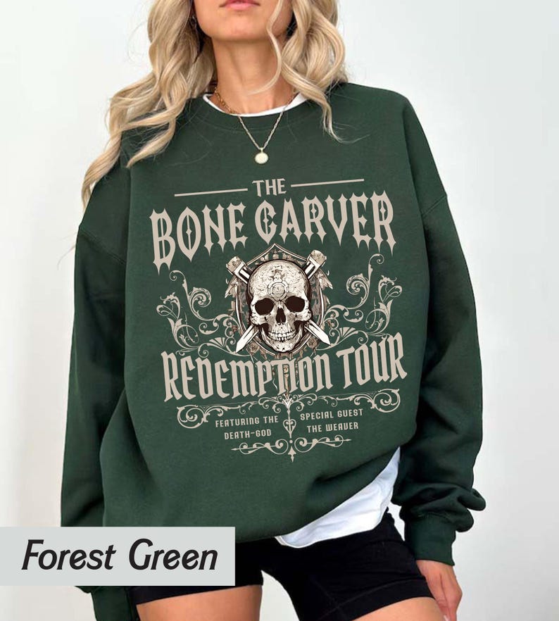 May include: Forest green sweatshirt with a graphic design. The design features the text "THE BONE CARVER REDEMPTION TOUR" with a skull and crossed swords. The sweatshirt is a solid color.