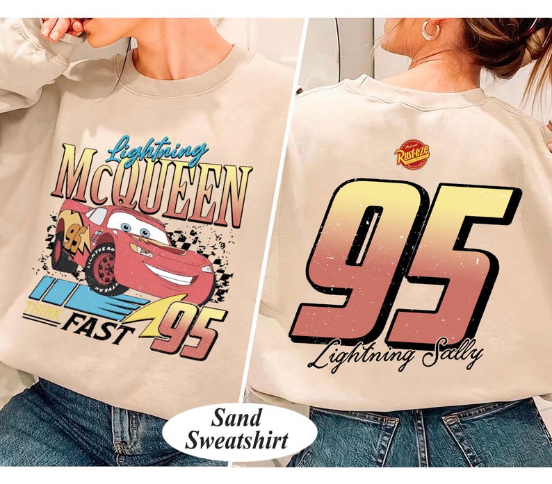 May include: Sand-colored sweatshirt featuring Lightning McQueen from the Cars movie. The front graphic shows McQueen with text "Lightning McQueen" and "FAST 95". The back displays a large "95" and "Lightning Sally" text.