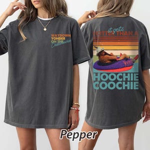 May include: Dark grey t-shirt with the text "WAYDOWN YONDER ON THE Chattahoochee" on the front. The back features a graphic of a person in a tube with the text "it gets hotter than a HOOCHIE COOCHIE".