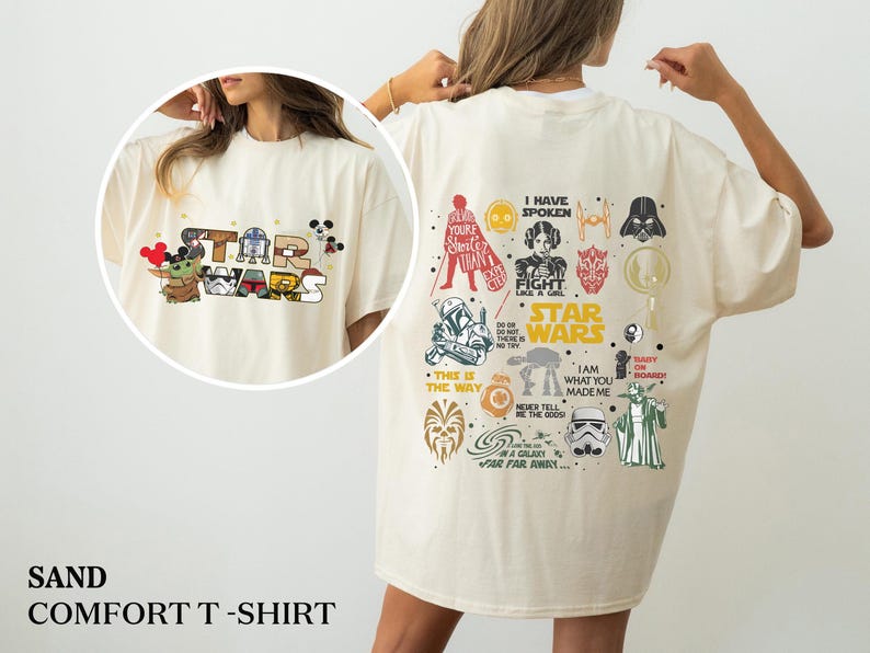 May include: Sand-coloured comfort t-shirt with Star Wars characters and logos. The front shows a Star Wars logo with Baby Yoda and Mickey Mouse ears. The back has various Star Wars graphics and text, including "I Have Spoken" and "This is the Way."