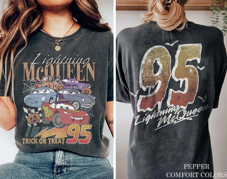 K&ouml;nnte beinhalten: Dunkelgraues T-Shirt mit einem Aufdruck von Lightning McQueen und anderen Cars-Charakteren mit dem Text "Lightning McQueen" und "Trick or Treat 95". Auf der R&uuml;ckseite steht "95 Lightning McQueen" mit Spinnennetz-Design.