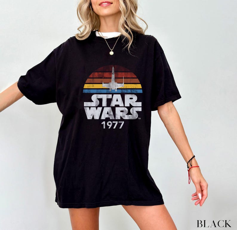 May include: Black t-shirt with a vintage Star Wars graphic featuring a spaceship and the text "Star Wars 1977".