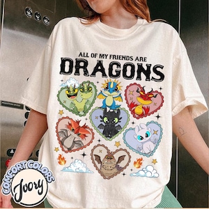May include: Ivory-colored t-shirt with the text "ALL OF MY FRIENDS ARE DRAGONS" in black. The shirt features colorful dragon illustrations inside heart-shaped frames. The Comfort Colors logo is visible on the bottom left.
